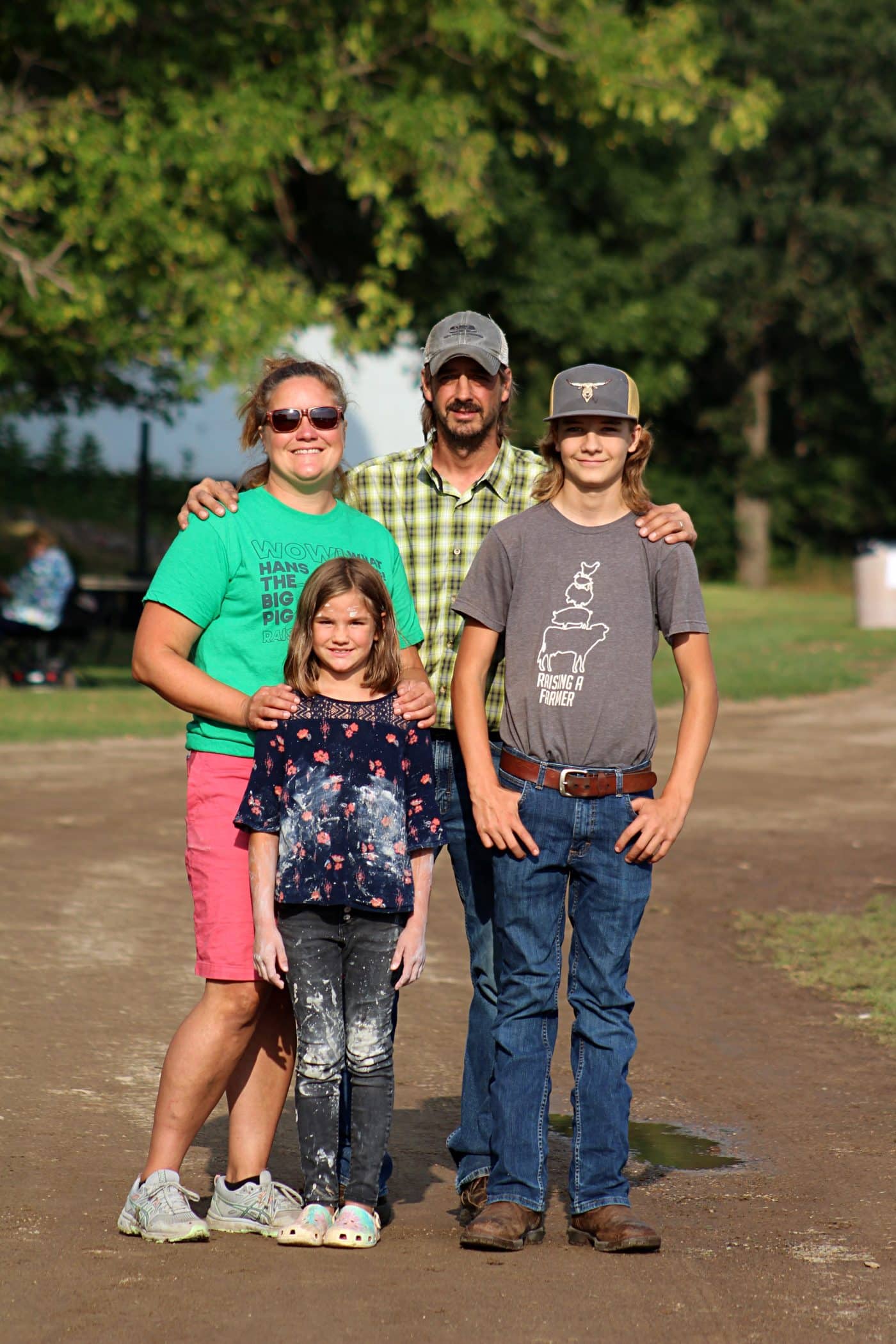 Brenda and Nate Rudolph with their children Everett and Vivian standing together and smiling on a gravel road.