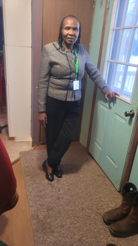 Jane Windsperger standing up and smiling indoors with her arm on a door.